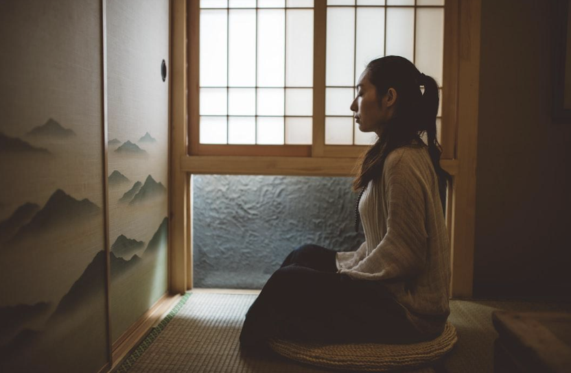 A person sitting quietly in meditation by a bright window